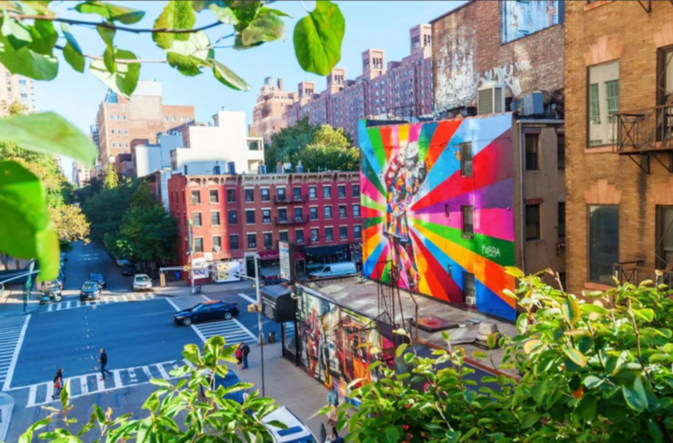 Colorful street art mural in NYC with buildings, trees, and vibrant urban culture scene