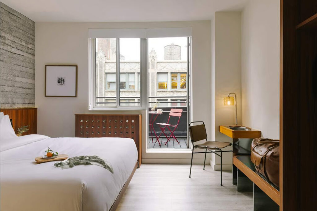 Hotel room with large window, natural light, comfortable bed, and sleek interior design