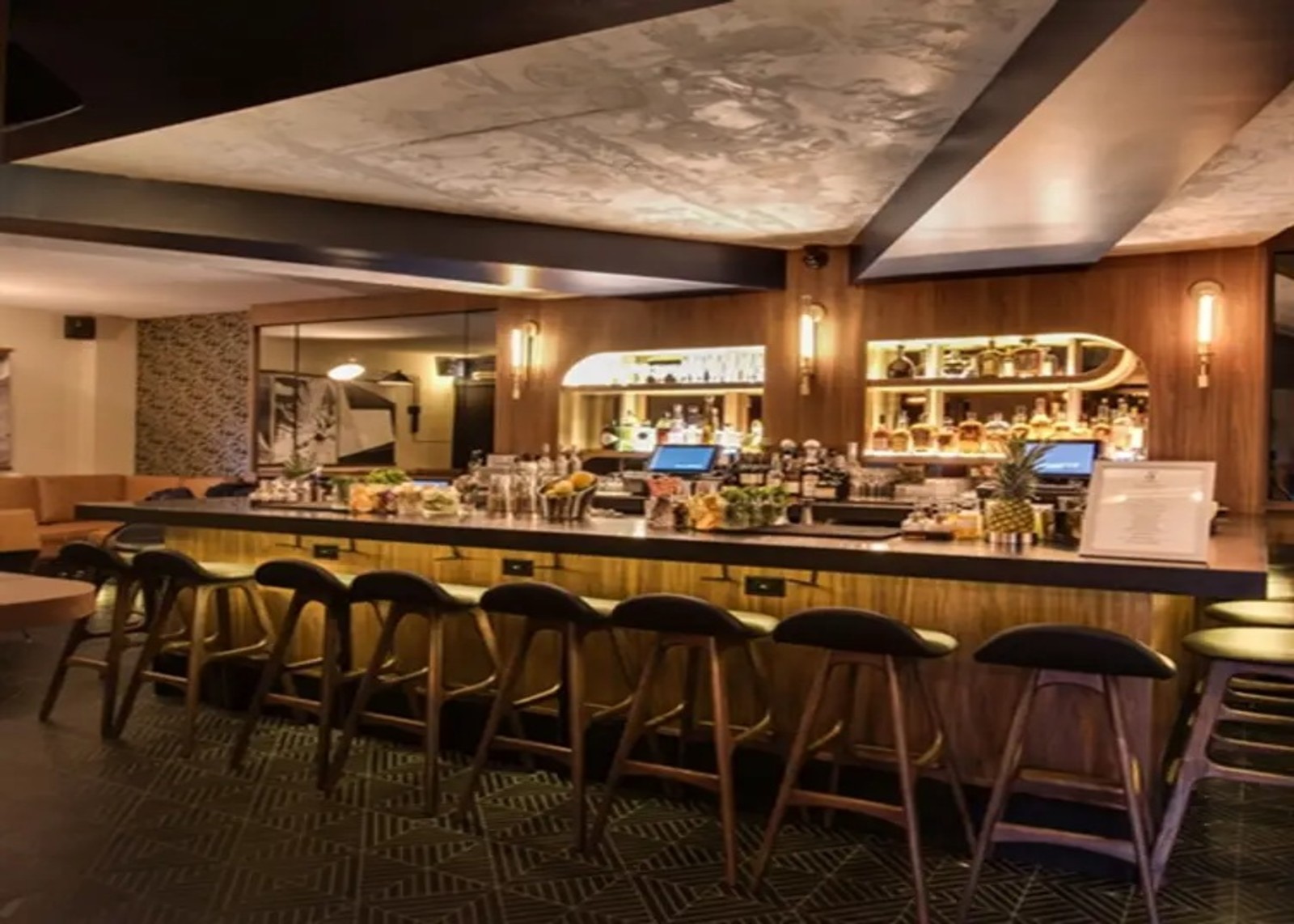 Cozy hotel bar with stylish seating, warm lighting, and premium drink setup at Hotel Henri NYC